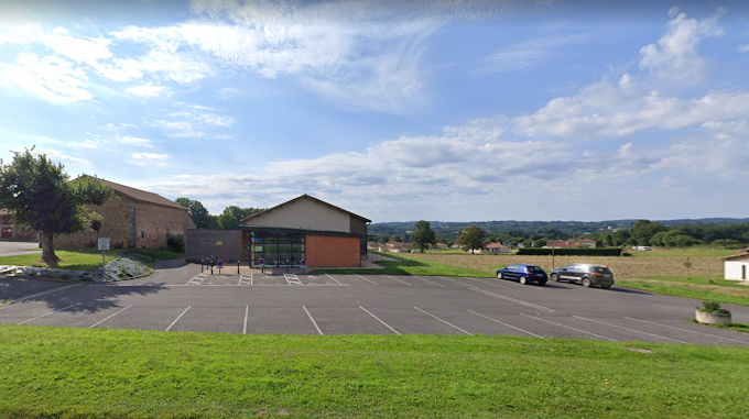 "Parking avec places marquées, véhicules et bâtiments en arrière-plan."