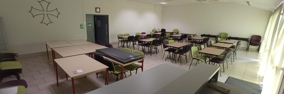 Salle de classe avec tables, chaises, tableau blanc et porte.