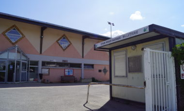 Bâtiment avec guichet extérieur, enseignes, portes vitrées et station de recharge.