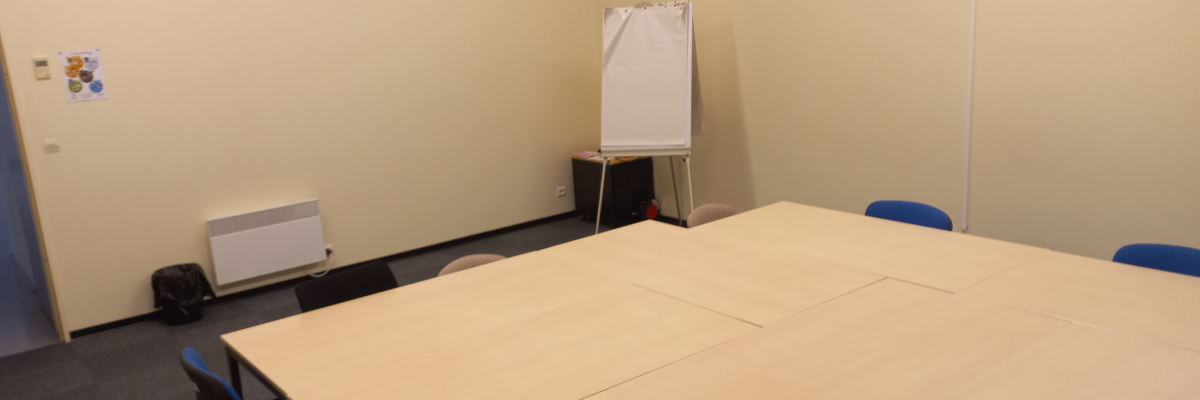 "Salle avec table, chaises, tableau blanc, climatiseur et radiateur."