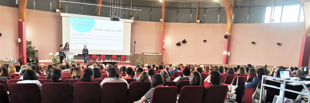 Salle de conférence avec écran, podium, chaises, projecteur et public.