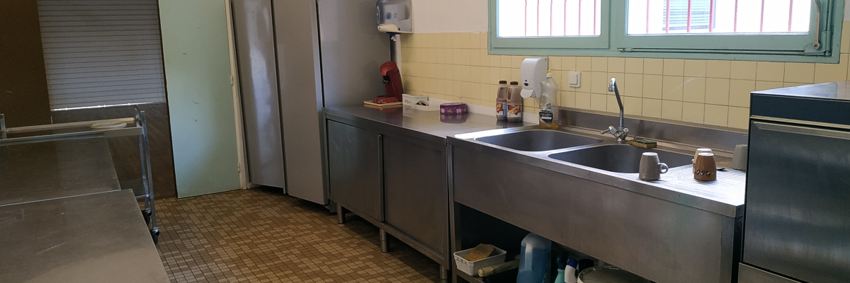 Cuisine avec plans de travail, éviers, réfrigérateurs, fenêtres et porte.