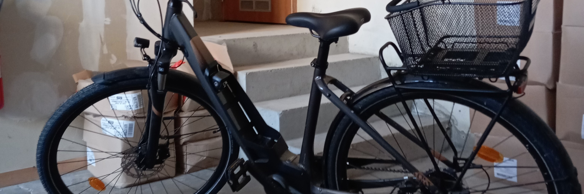 Vélo noir avec panier et brique près d'une porte.