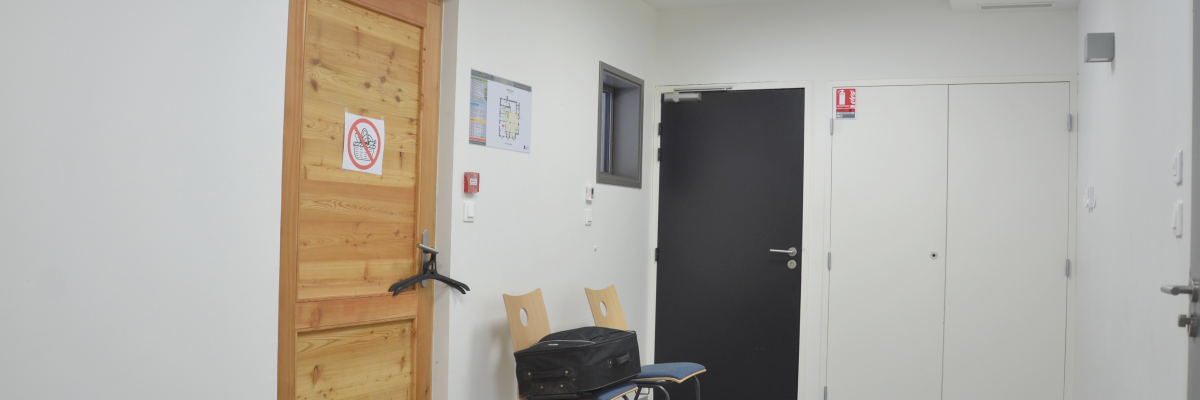 Pièce avec porte en bois, chaises, sacs et sac à dos.