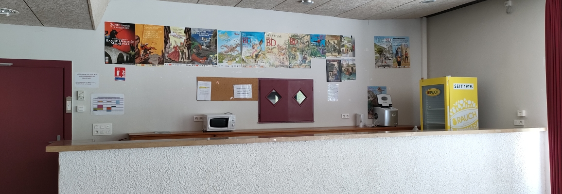 Réception avec comptoir, distributeur de boissons, affiches murales et tablette.