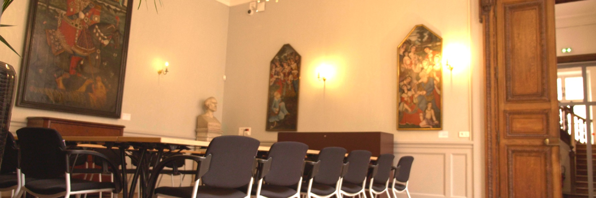 Salle avec table, chaises, peintures, lustre, porte, et plantes.
