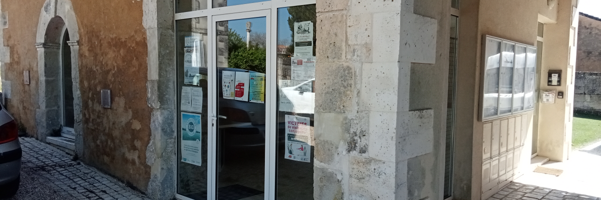 Bâtiment avec porte, fenêtres et affiches.