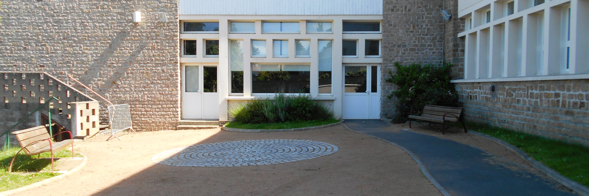 Bâtiment avec escaliers, allée, fenêtres et bancs.