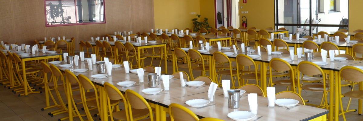 Cantine avec tables, chaises, vaisselle et verres.