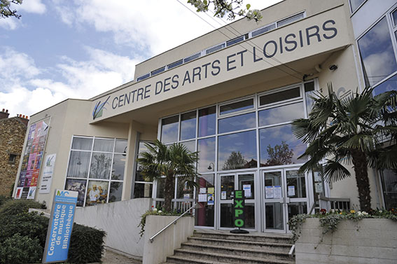 Bâtiment avec enseigne "Centre des Arts et Loisirs", vitres, entrance, plantes, affiches.