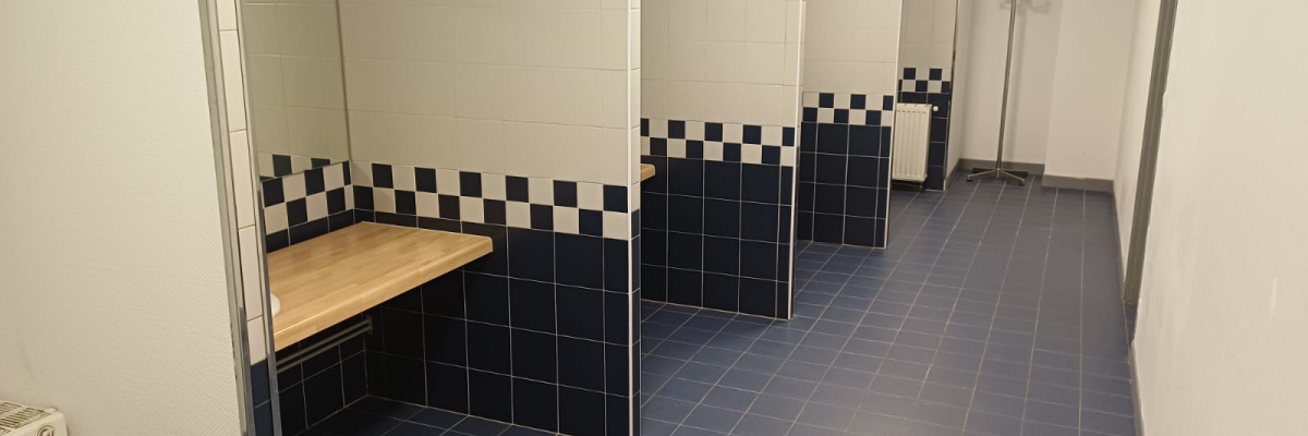 Toilettes avec lavabos, miroirs, portes et carrelage bleu et blanc au sol et sur les murs.