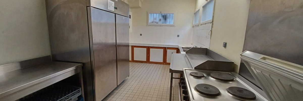 Cuisine équipée avec réfrigérateur, plaques de cuisson, évier, plans de travail et armoires.