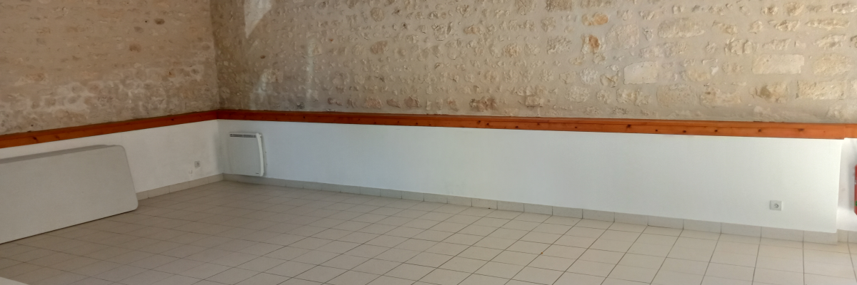 Salle avec mur en pierre, radiateur et banc.