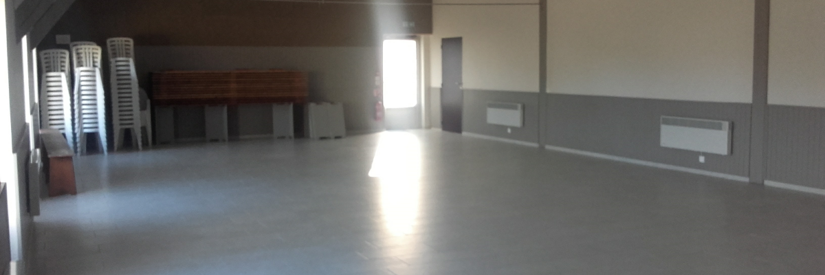 Salle vide avec chaises empilées, radiateurs et un banc.