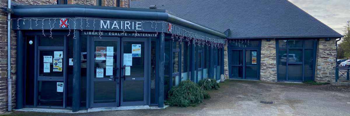 Bâtiment de mairie avec façade en pierre et entrées vitrées, parking devant.