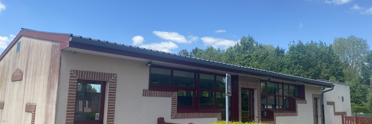 Bâtiment avec porte, fenêtres et clôture.