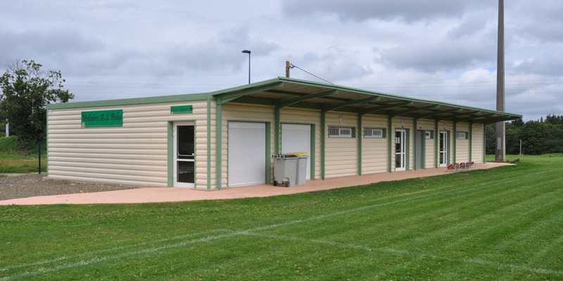 Bâtiment avec portes, fenêtres et climatiseur extérieur sur terrain gazonné.