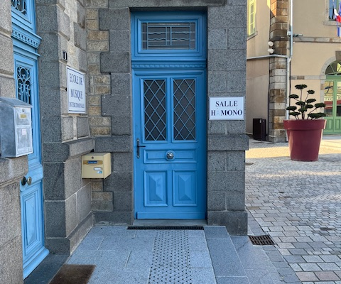 Entrée bleu avec plaque, boîte aux lettres et pot de fleurs.