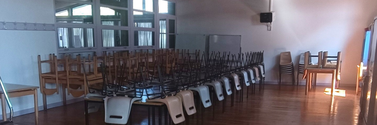 Salle de classe avec tables, chaises et sac à dos.