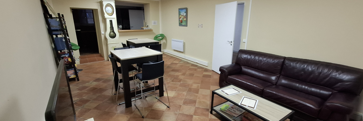 Pièce avec canapé, table basse, table, chaises, étagères, porte, radiateur et horloge.