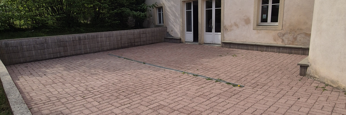 Cour pavée devant un bâtiment avec porte et fenêtres.