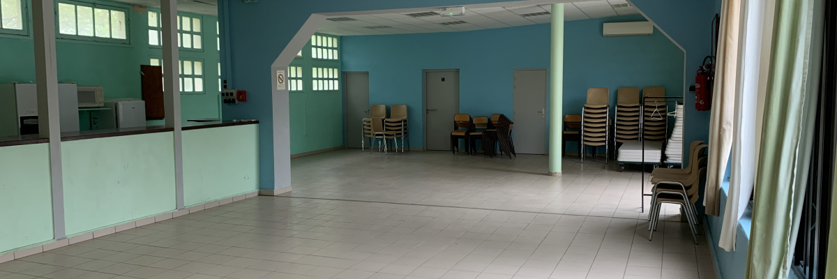 Salle avec chaises, tables, comptoir, fenêtres et rideaux.