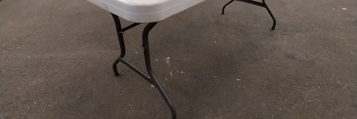 Table blanche sur tréteaux dans un entrepôt.