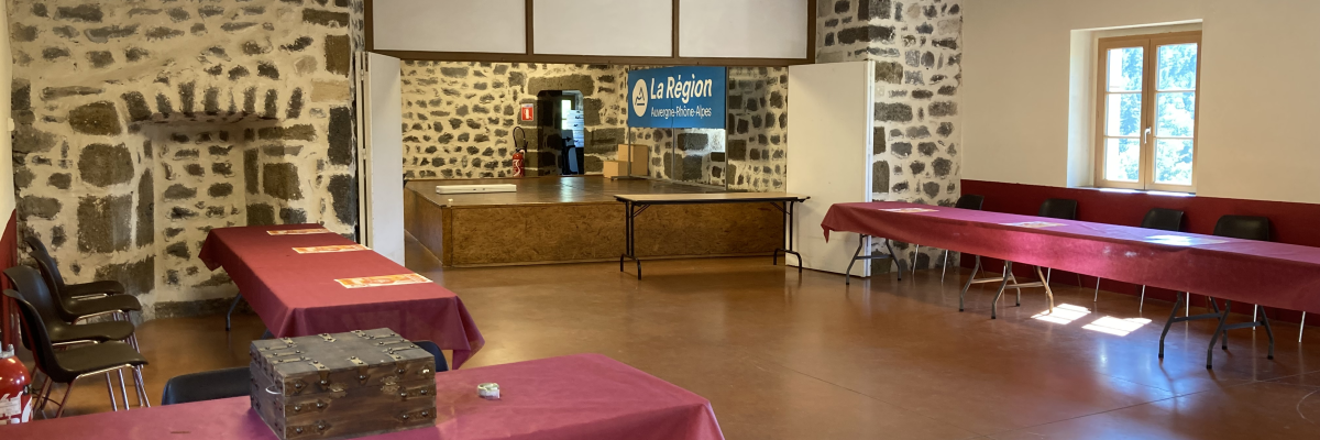 Salle avec tables couvertes, chaises, buffet et affiches murales.