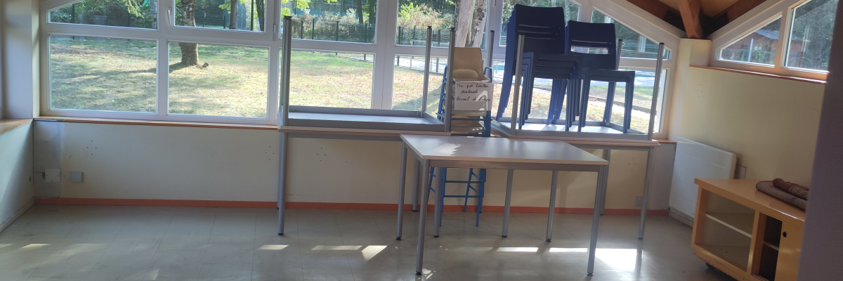 Salle avec table, chaises, piano, et grandes fenêtres.