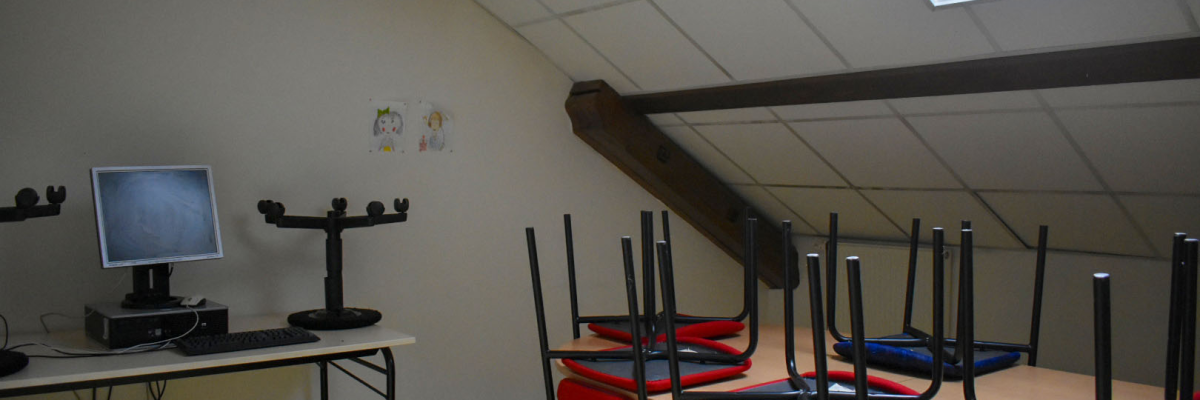 Salle avec ordinateur, écran, trampolines et fenêtres.