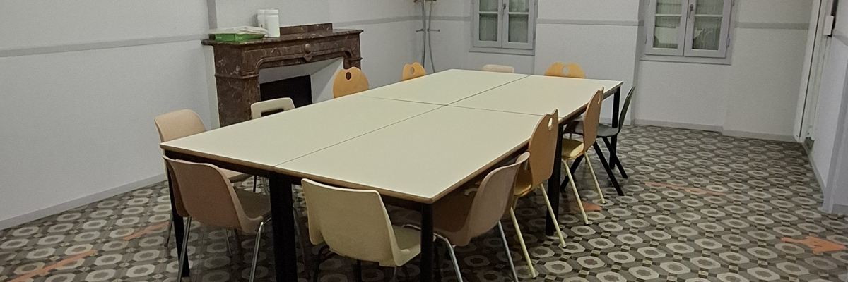 Salle avec table, chaises, meuble et éclairage.