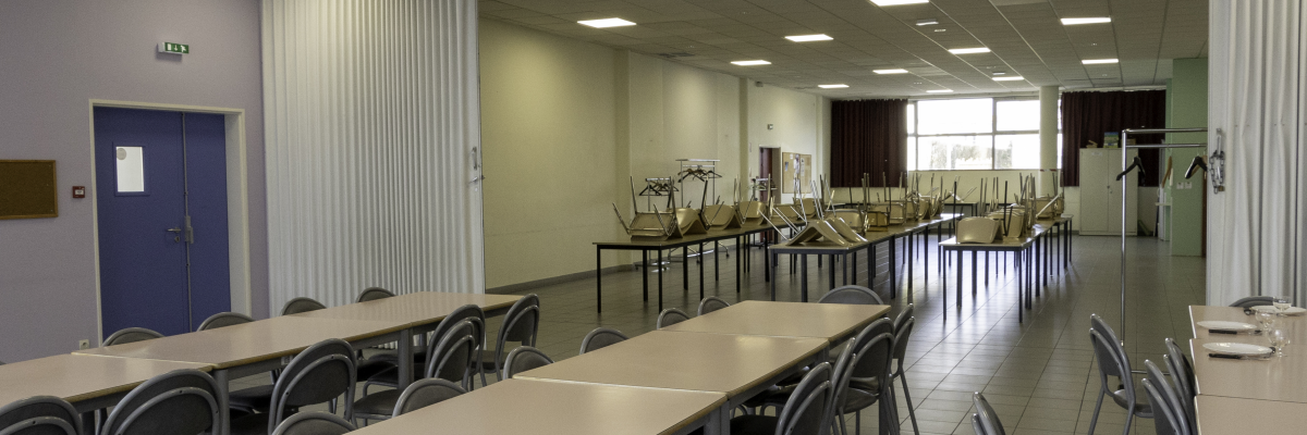 "Salle avec tables, chaises, vélo d'appartement, rameur et miroir en fond."