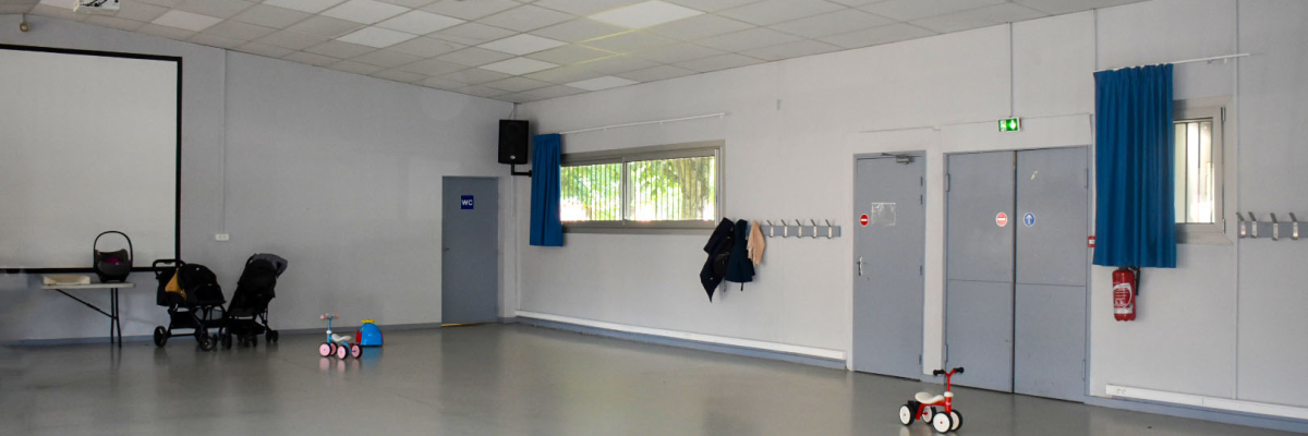 Espace vide avec porte, fenêtre, extincteur, tricycle, poussette, voiture pour enfant, tableau blanc.