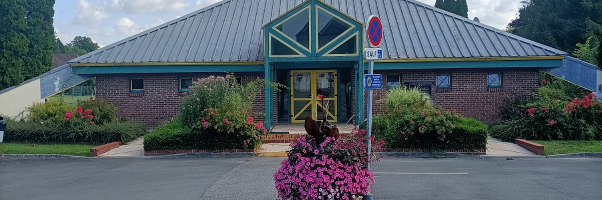 Bâtiment avec parking, fleurs, panneau "arrêt" et "handicapé".