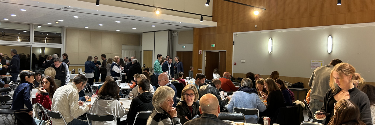 Salle de réception avec tables, chaises, et personnes assises et debout.