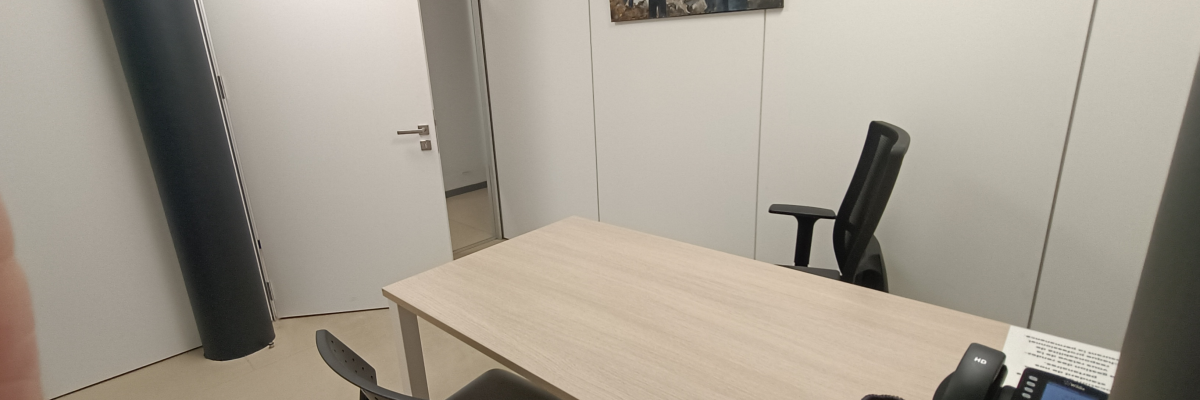 Salle de réunion avec table, chaises, téléphone et tableau.