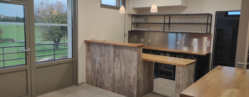 Cuisine avec comptoir, étagères, plaques de cuisson, four, hotte, réfrigérateur et table.