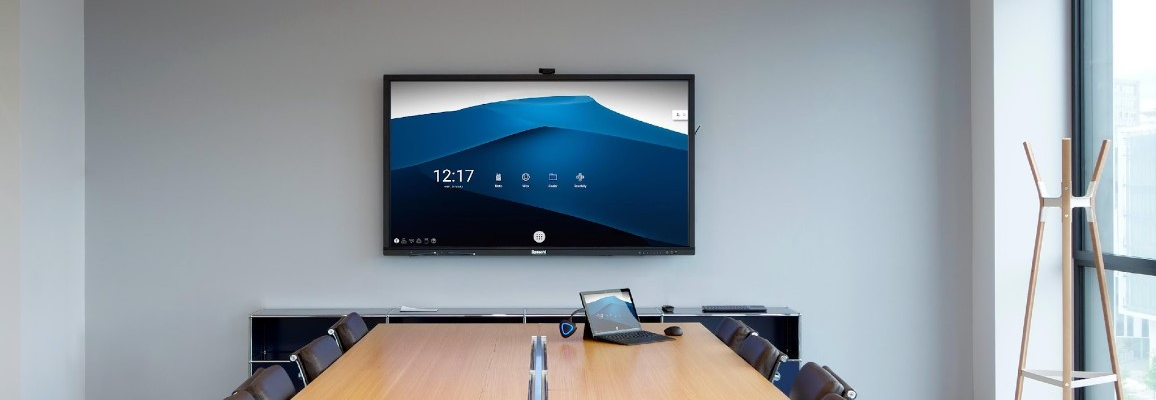 Salle de réunion avec table, chaises, écran, ordinateur portable, support pour écouteurs et lumière circulaire.