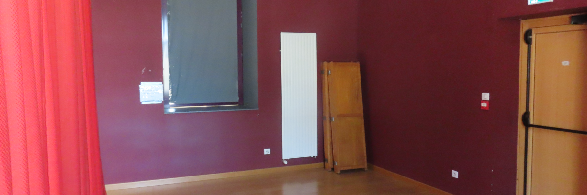 Pièce vide avec porte, fenêtre, rideau rouge, porte en bois et sol en parquet.