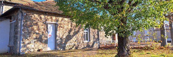 Un bâtiment en pierre avec une porte blanche et des arbres à l'extérieur.