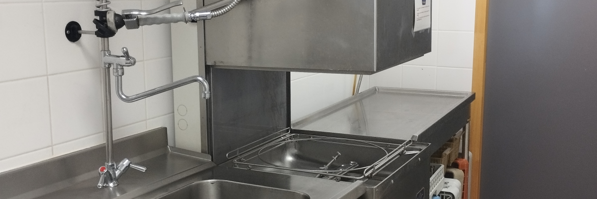 Cuisine avec évier, lave-vaisselle, tuyau flexible et extincteur.