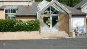 Entrée d'un bâtiment avec buissons, marches et rampes.