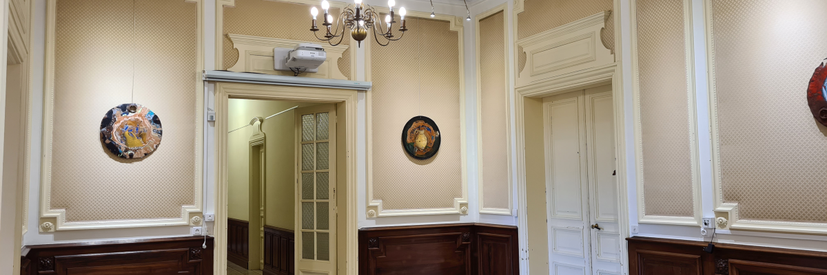 Salle avec lustre, tableaux, portes et boiseries.