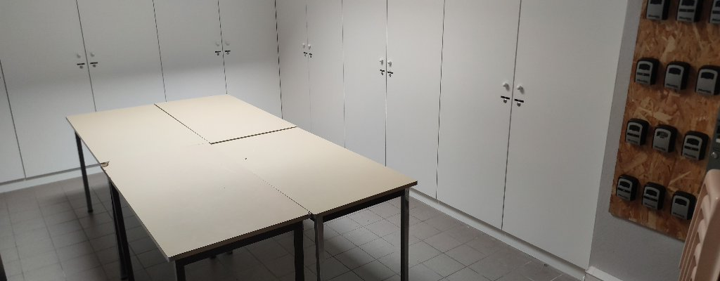 Salle avec table, chaises, armoires et tableau électrique.