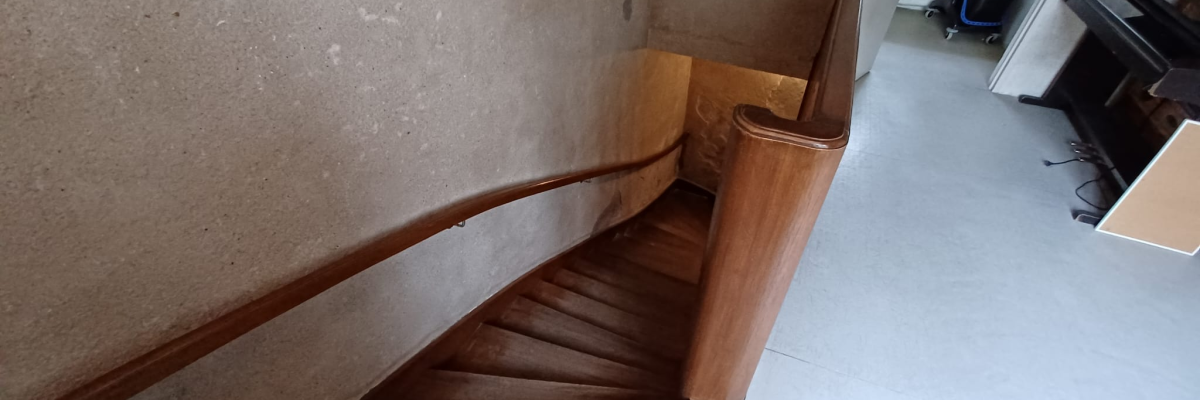 Escalier en bois, mur de briques, pièce avec lave-linge et sèche-linge.