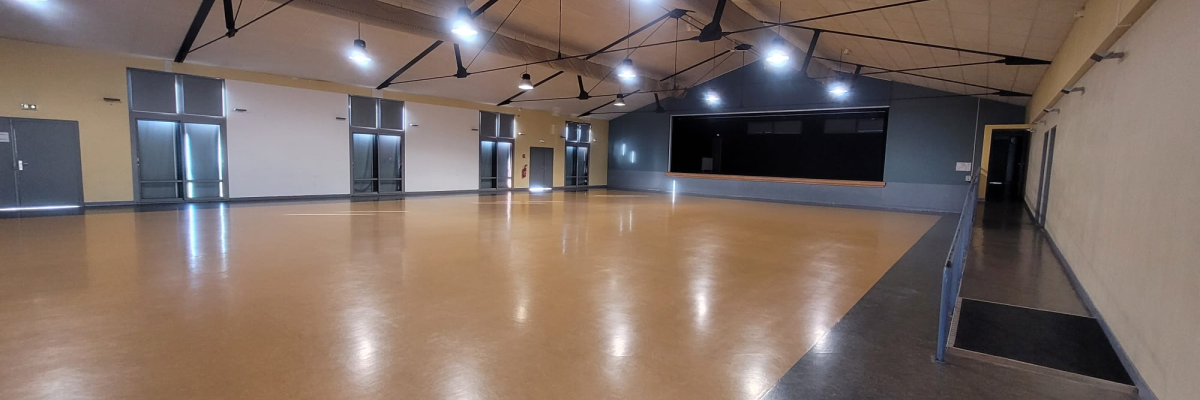Salle avec sol lisse, éclairage suspendu, miroirs et portes.