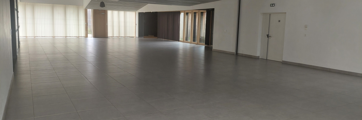 Salle vide avec sol carrelé, portes et fenêtres.