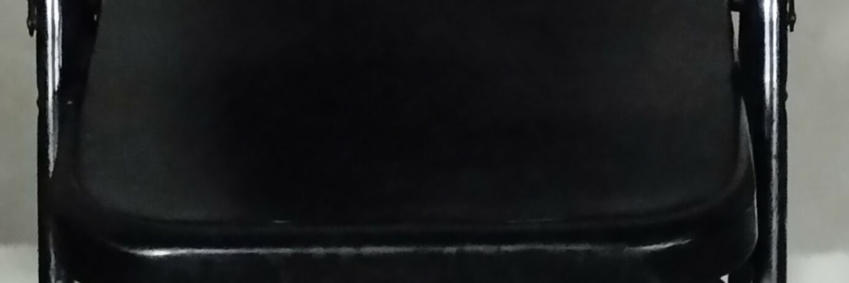 Chaise pliable noire avec dossier et siège rembourrés.