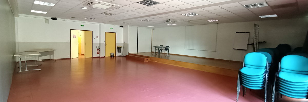 Salle avec tables, chaises et tableau blanc.