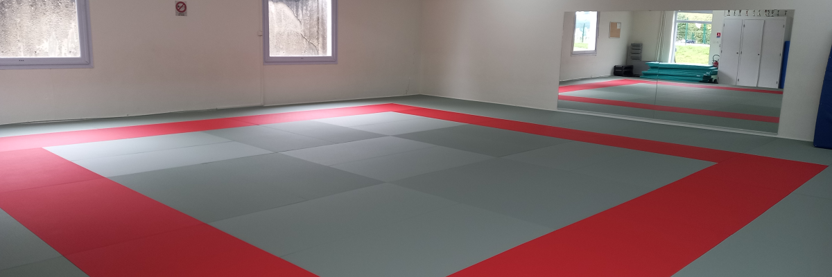 Salle avec sol de sport, miroirs, fenêtres et extincteur.